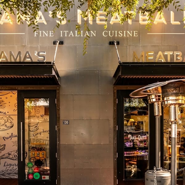 Mama's Meatball restaurant exterior with two doors, a "Take Out" sign, and outdoor heaters.